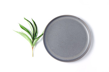 composition of gray plate and green leaves. white background, view from the top