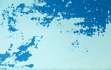 Two coats of old blue paint that has lost its color and has fallen off in the sun, on an uneven old surface