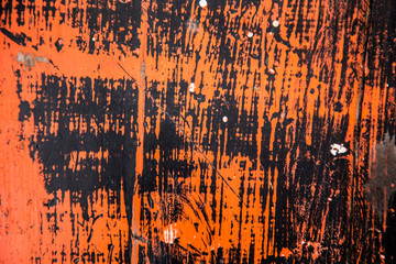 Old wooden surface, covered with two colors of paint, black and orange, which have lost their color in the open sun and in some places fell off, revealing the background