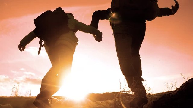 happy family dad with daughter teamwork tourists silhouette concept. slow motion video. dad and daughter with backpacks run up the hill and jump lifestyle . man and young girl walking hiking