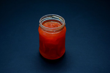 Glass jar of jam on a dark background