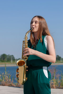 Young woman with saxophone in the park