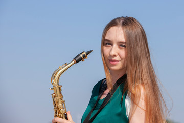 Young woman with saxophone with nature background
