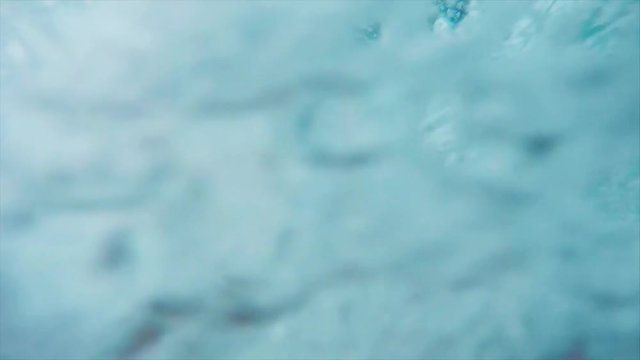 Slow motion go pro view of man's feet sliding down water slide and splashing into swimming pool