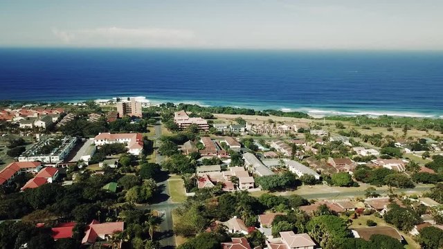 Aerial footage filmed by a Drone of Scottburgh Beach and Land grassy fields with residential houses overlooking the sea in Kwa Zulu Natal South Africa