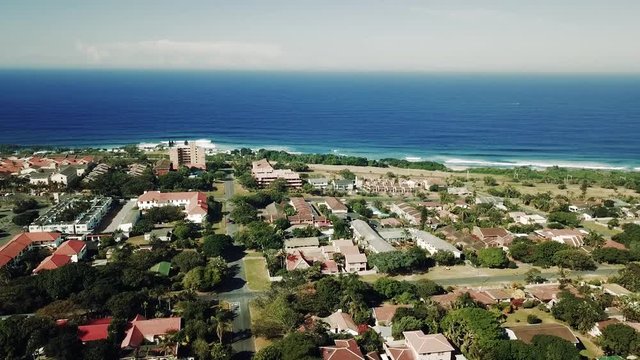 Aerial footage filmed by a Drone of Scottburgh Beach and Land grassy fields with residential houses overlooking the sea in Kwa Zulu Natal South Africa