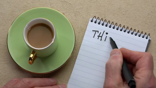 think win-win - man hand writing a note with a black marker in a spiral notebook, overhead view