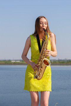 Young woman with saxophone with nature background