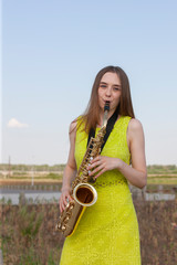 Beautiful brunette plays the saxophone in the park