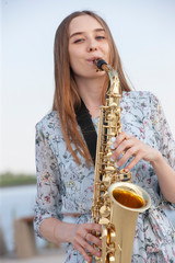 Beautiful brunette plays the saxophone in the park