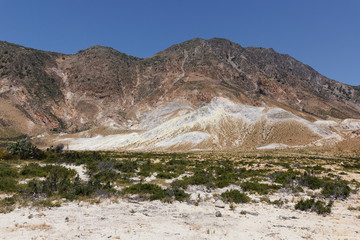view of the Caldera of the volcano on Nisyros, a huge crater with snow-white sediments, sulfur crystals, from a height, the landscape around resembles a desert