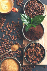 Coffee beans, milled coffee and spices on dark background