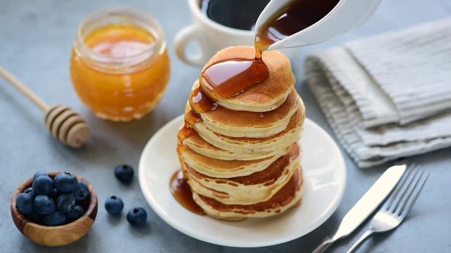 Pouring maple syrup on stack of delicious buttermilk pancakes. Real time footage, tasty food