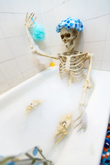 Bony skeleton taking a bubble bath in a grungy off-white dirty tub