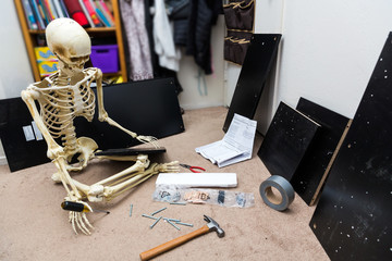 Bony skeleton assembling a black wooden shelf