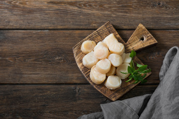 Raw scallops on wooden Board on wooden background