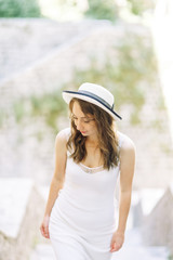 Summer photo shoot on the streets of Kotor, Montenegro. Beautiful girl in white dress and hat.