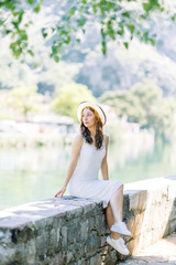 Summer photo shoot on the streets of Kotor, Montenegro. Beautiful girl in white dress and hat.
