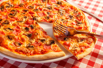Pizza with ham and mushrooms. Delicious hot food sliced and served on white platter. Menu photo, Italian fast food.