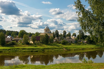 View of the left bank of the river Msta and the Church of the Assumption of the Blessed Virgin Mary on a summer day