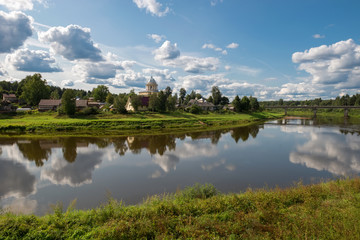 View of the left bank of the river Msta and the Church of the Assumption of the Blessed Virgin Mary on a summer day