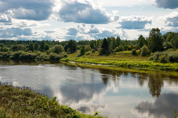 River landscape. River Msta and clouds reflected in the water on a summer day