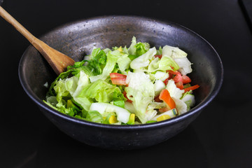 Healthy vegetable salad of fresh tomato, cucumber, onion, spinach, lettuce and sesame on plate. Diet menu