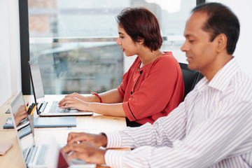 Business people sitting at the table and concentrating on their work they typing on laptop computer at office