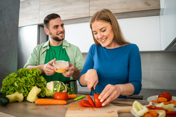 Young couple is preparing meal in their kitchen. 
