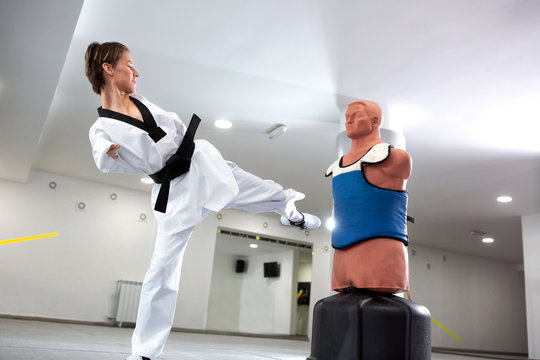 Young woman with physical disability performing kicks on a punching dummy