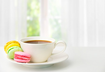 A mug of tea and colored biscuits  on a white table