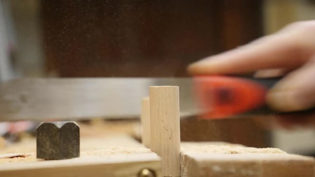 4K Footage of a carpenters hand sawing wood with a cloud of saw dust being generated.