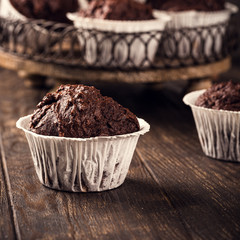Tasty chocolate banana muffins on dark wooden table. Sweet mini cakes. Party food background with copy space.