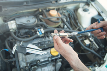Technician installing new candle in car engine.