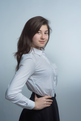Portrait of a young beautiful brunette with lush curly hair in a white shirt and gray skirt