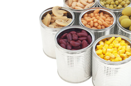 Many canned food: green peas, beans, corn, olives and mushrooms in tin cans isolated on white background.