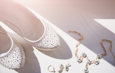 Bride's shoes with diamond crystals. Perfumes and earrings accessories. Wedding day photo.
