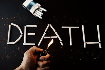 Death sign from cigarettes. Dangerous habit. Harmful for health. Man holds lighter in hands.