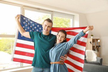 Young couple with USA flag at home. Independence Day celebration