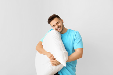 Handsome man hugging pillow against white background