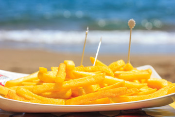 Fried french fries on the beach against the background of the sea