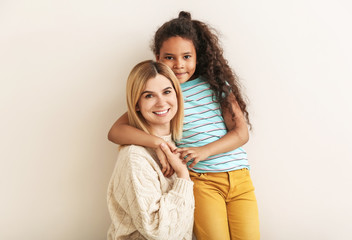 Happy woman with little adopted African-American girl on white background
