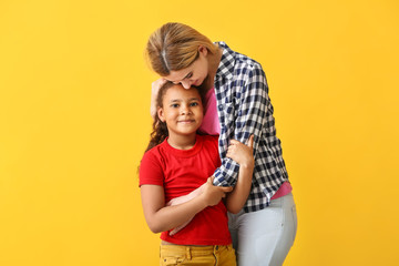 Happy woman with little adopted African-American girl on color background