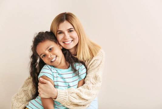 Happy woman with little adopted African-American girl on white background
