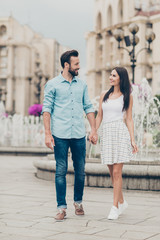 Fulll length body size view photo positive cheerful people millennial free time voyage weekend tourist visitor buildings fountain content rejoice fun denim jeans shirt blue dress sneakers bearded