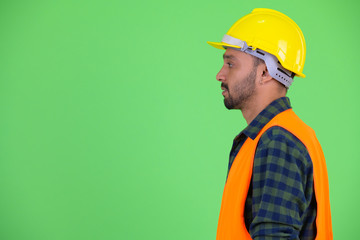 Profile view of young bearded Persian man construction worker