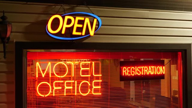 Signs are lit up signaling where the registration is for checking in at a motel.