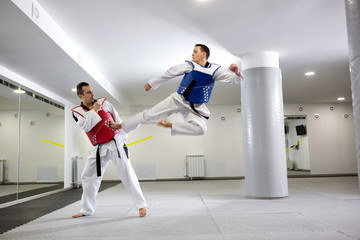 Two sportsman practicing taekwondo while training together
