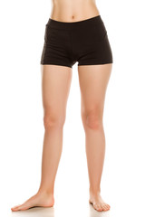 Female barefoot legs in black sport shorts on white background