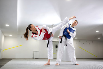 Young woman training martial art of taekwondo with her coach - obrazy, fototapety, plakaty